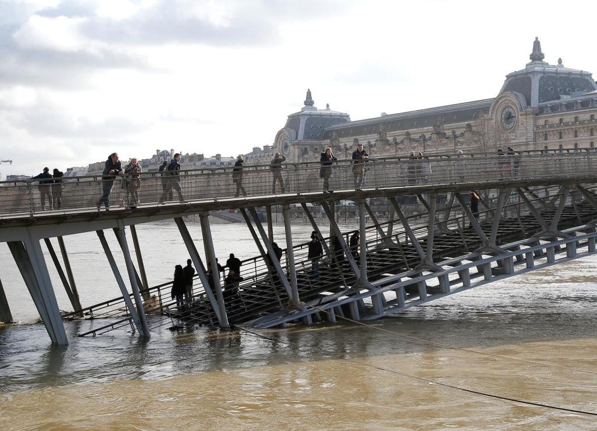 Varias personas observan las inundaciones del Sena desde el puente Leopold-Sedar-Senghor en París.