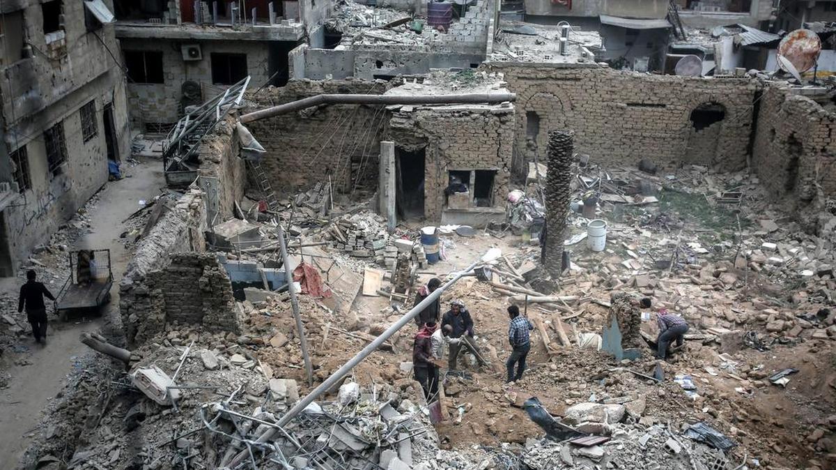 Varias personas buscan sus pertenencias entre los escombros de los edificios tras los ataques aéreos del pasado 25 de febrero en Douma, Siria, el 28 de febrero de 2017.