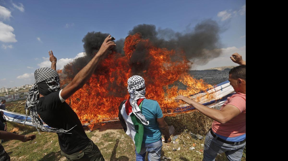 
Varios palestinos queman una bandera de Israel durante los enfrentamientos con soldados israelíes registrados cerca de la prisión de Ofer, a las afueras de la ciudad cisjordana de Ramalá, el viernes.
