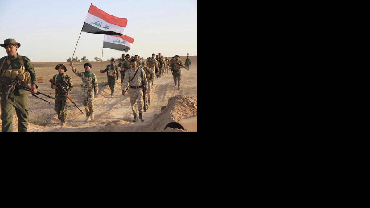 
Soldados iraquíes y miembros de las milicias chiitass denominadas “Multitud Popular” caminan con banderas nacionales en Tikrit, Irak, el martes.
