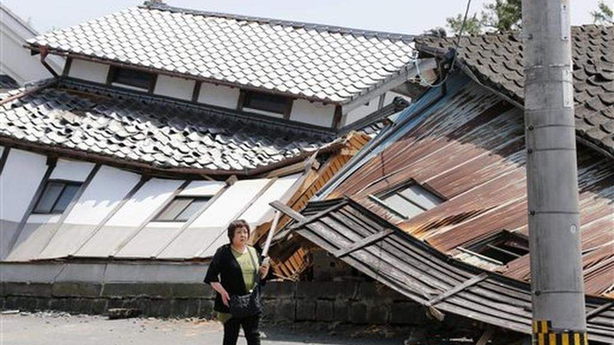 Una mujer pasa por delante de viviendas destruidas por un sismo registrado en la víspera en Mashiki, en la prefectura de Kumamoto, en el sur de Japón, el 15 de abril de 2016. (Naoya Osato/Kyodo News via AP) JAPAN OUT, MANDATORY CREDIT