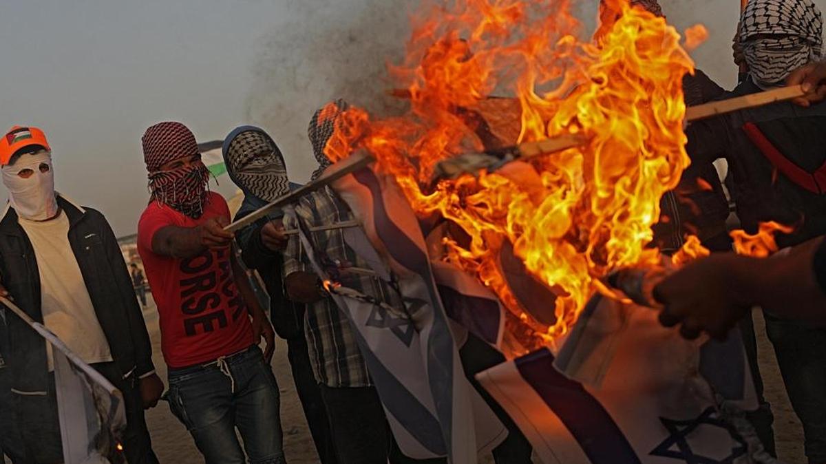 Manifestantes palestinos queman banderas israelíes durante una protesta cerca de la frontera con Israel el martes 17 de abril de 2018, en el este de la Ciudad de Gaza (Gaza).