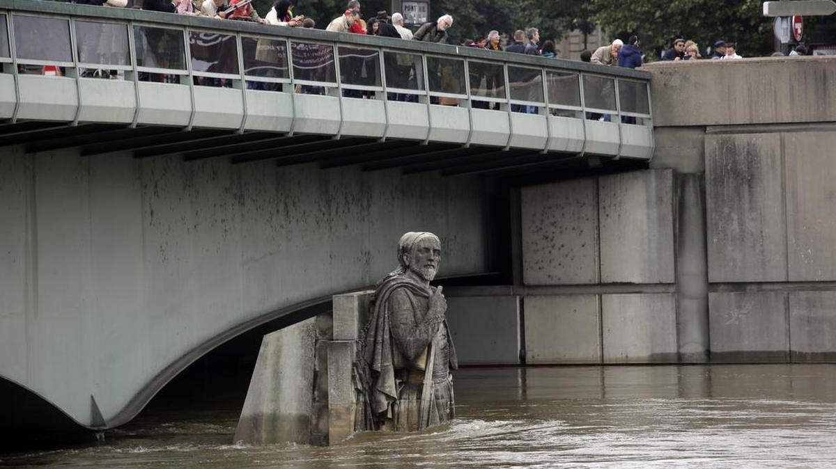 Desde un puente, los parisinos miran al peligroso nivel del agua en el río Sena.