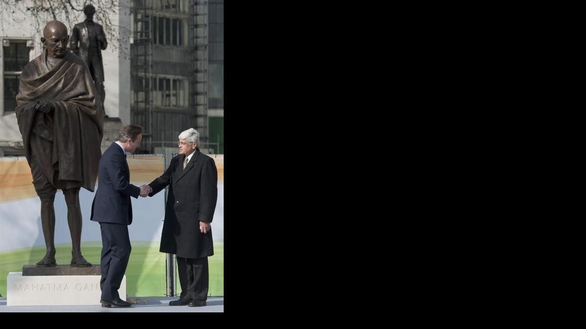 <cutline_leadin>El Primer</cutline_leadin> Ministro británico, David Cameron (izq.), saluda al nieto de Gandhi, Gopalkrishna Gandhi, junto a la estatua de bronce en la Plaza del Parlamento.<252>