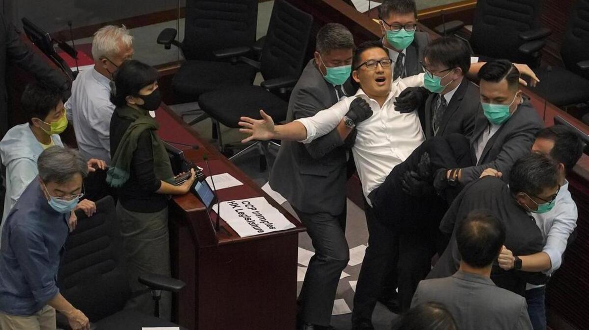 Guardias de seguridad se llevan a un manifestante durante una reunión del Comité de la Cámara del Consejo Legislativo en Hong Kong, el 18 de mayo del 2020.