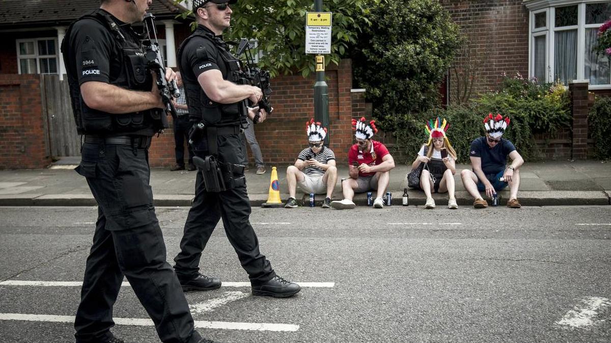 Policías patrullan el área mientras que los partidarios se sientan en el pavimento, antes de la final de la liga de Rugby en Twickenham, Londres, el sábado 27 de mayo de 2017.