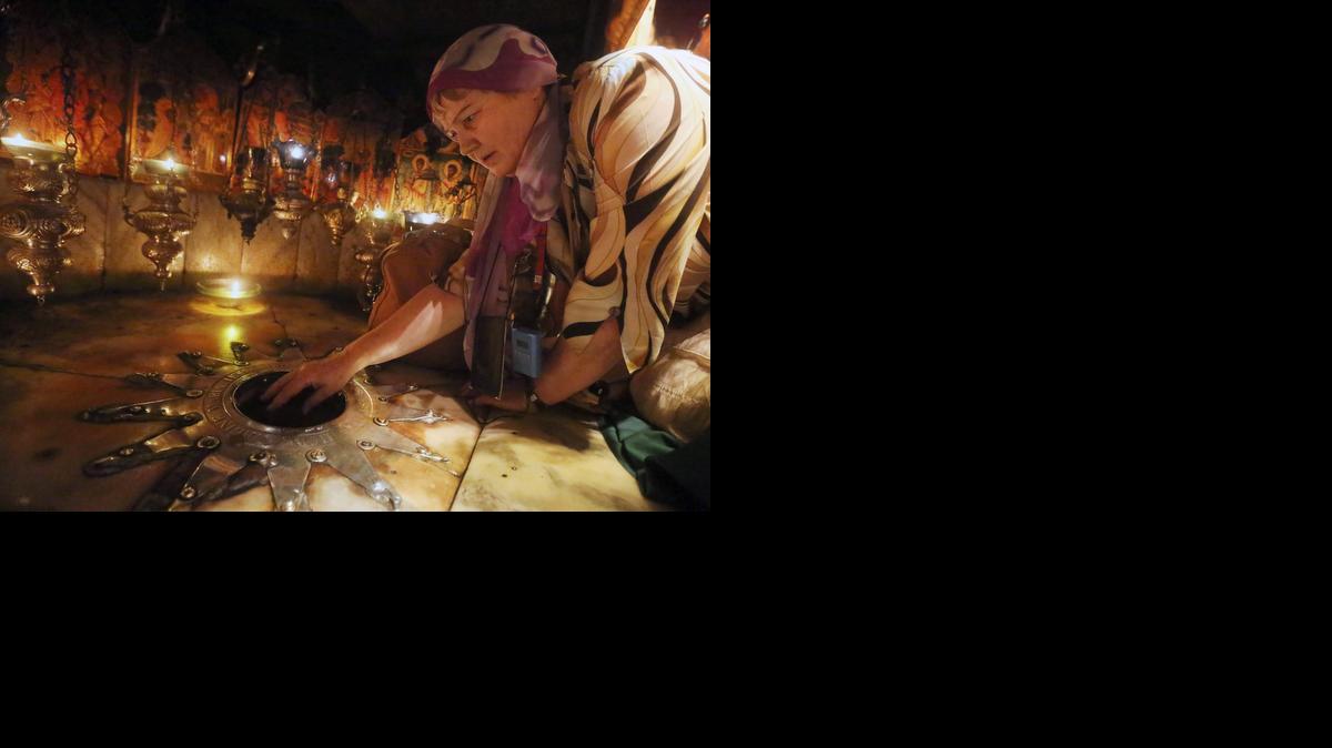 <cutline_leadin>Una mujer</cutline_leadin> cristiana toca la estrella de plata que marca la ubicación donde según la tradición Jesucristo nació en la ciudad de Belén.<252><252>