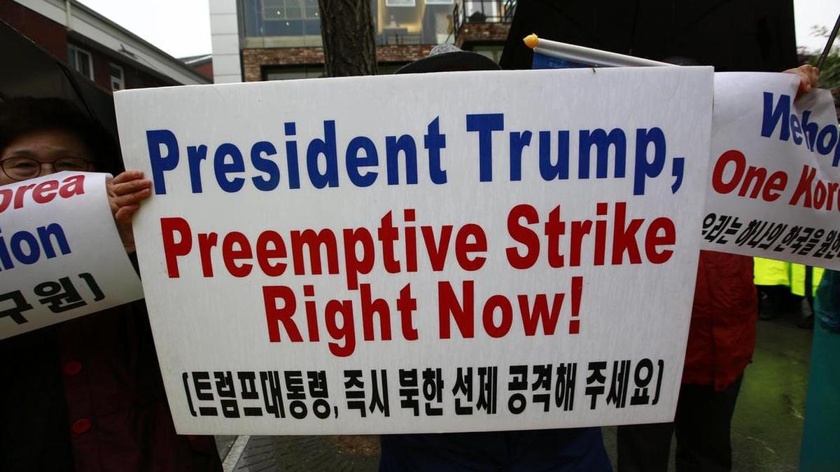 Un surcoreano sostiene una pancarta que reza "Presidente Trump, ataque preventivo ahora mismo" mientras varios surcoreanos dan la bienvenida al vicepresidente de los Estados Unidos, Mike Pence, en Seúl (Corea del Sur) el 17 de abril de 2017.