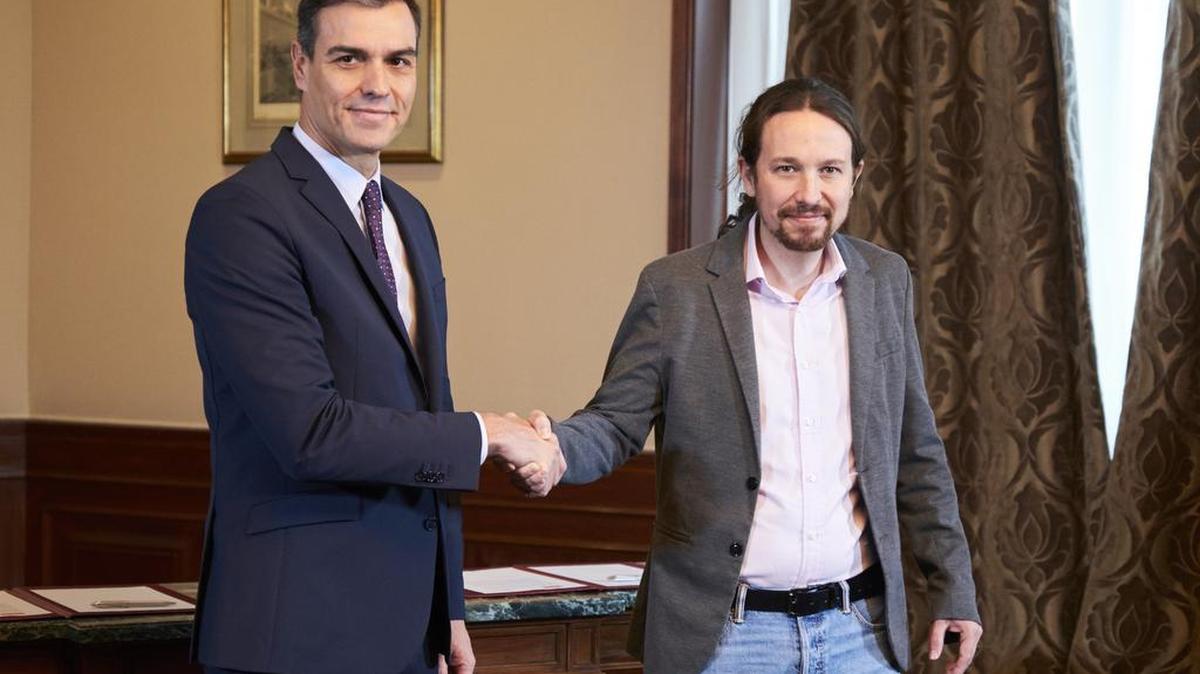 Pedro Sánchez (izq.), líder del Partido Socialista (PSOE), y Pablo Iglesias, líder de Unidas Podemos, se dan la mano tras acordar un compromiso para formar un gobierno de coalición en España, el martes en Madrid.