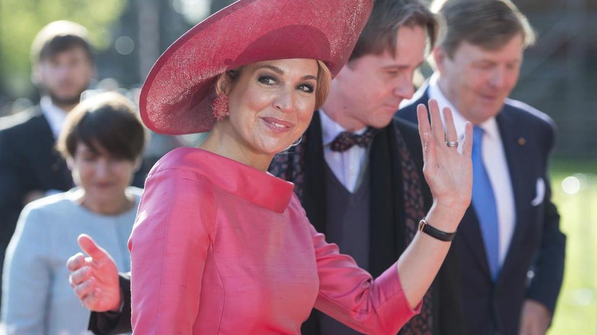 El rey Guillermo-Alejandro (d, al fondo) y la reina Máxima de Holanda (i) saludan a su llegada al Alte Pinakothek en Múnich (Alemania) el 13 de abril de 2016.