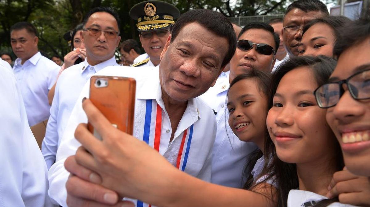 El presidente de Filipinas, Rodrigo Duterte posa para una selfie con los estudiantes después de una ceremonia de colocación de corona para conmemorar el Día Nacional de los Héroes en el Cementerio Heroes en Manila el 27 de agosto de 2018.