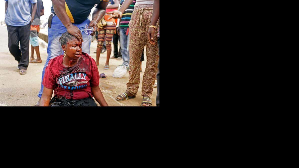 
Un hombre lava la cara de una mujer que fue golpeada por un policía en un centro de votación el sábado, en Lagos, Nigeria. 
