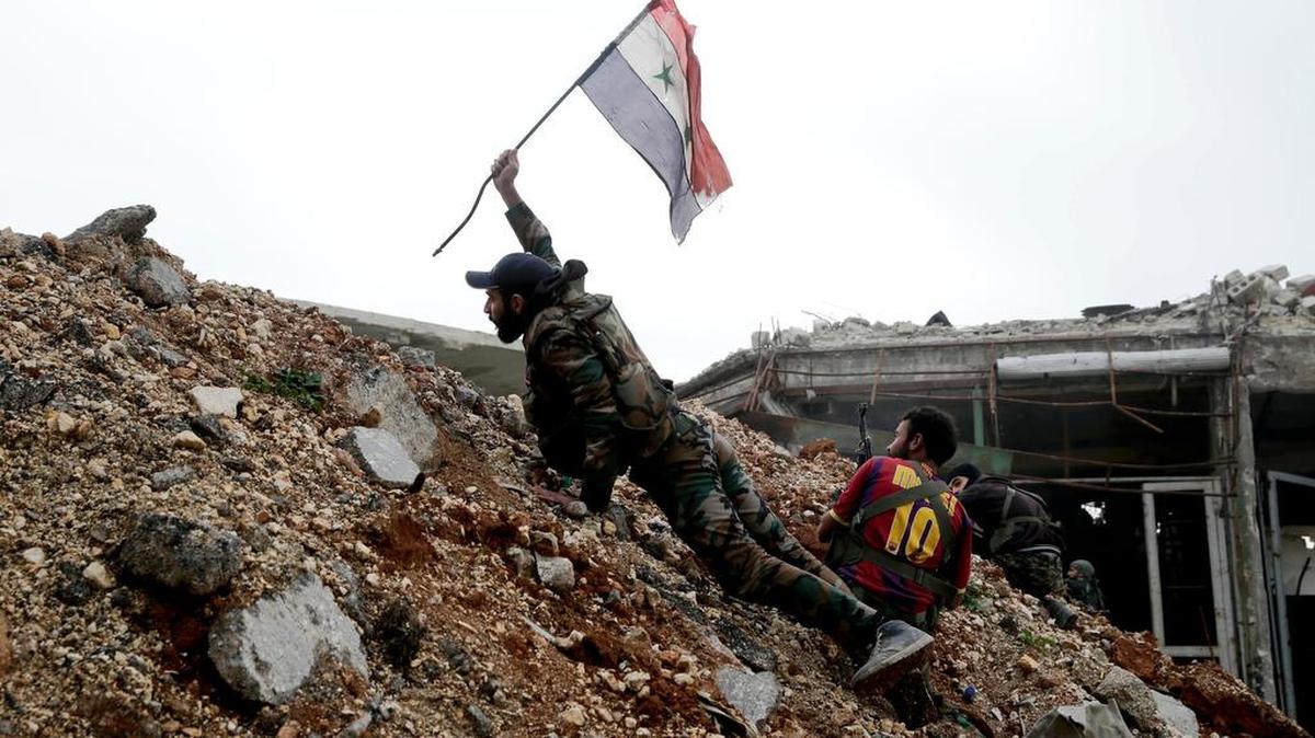 Un soldado del ejército sirio coloca una bandera nacional durante una batalla con los combatientes rebeldes, en la línea frontal de Ramouseh, al este de Alepo, Siria.