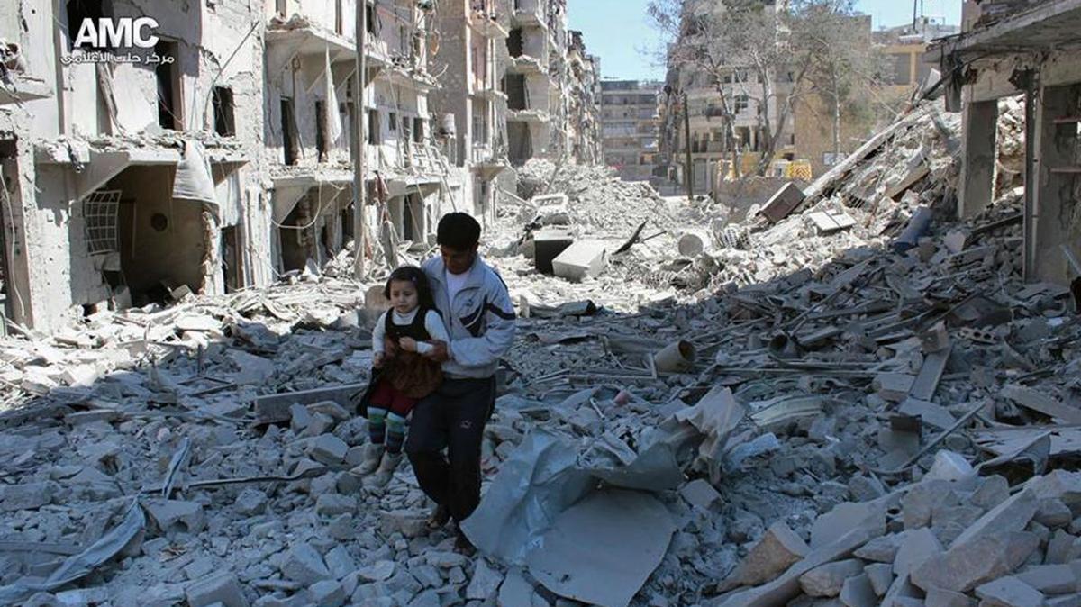 En esta foto de archivo de Aleppo Media Center (AMC), se ve a un hombre con una una niña en medio de un barrio destruido.