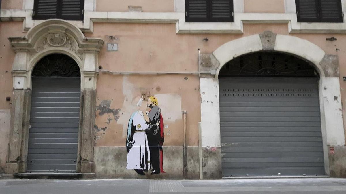 Un dibujo en el que el papa Francisco -identificado como un ángel- y el presidente de Estados Unidos, Donald Trump, caracterizado como un demonio, se besan en la boca apareció hoy en un muro en el centro de Roma, a poca distancia de del Vaticano.