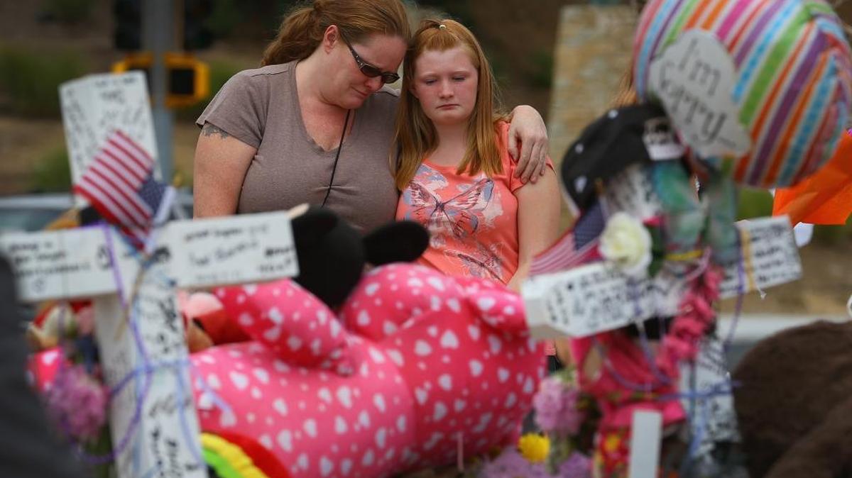 Carrie Hensley (izq) y Hailee Hensley se abrazan frente a un tributo hecho frente al cine Century 16 en Aurora, Colorado, donde James Holmes abrió fuego dejando 12 muertos y 58 heridos.