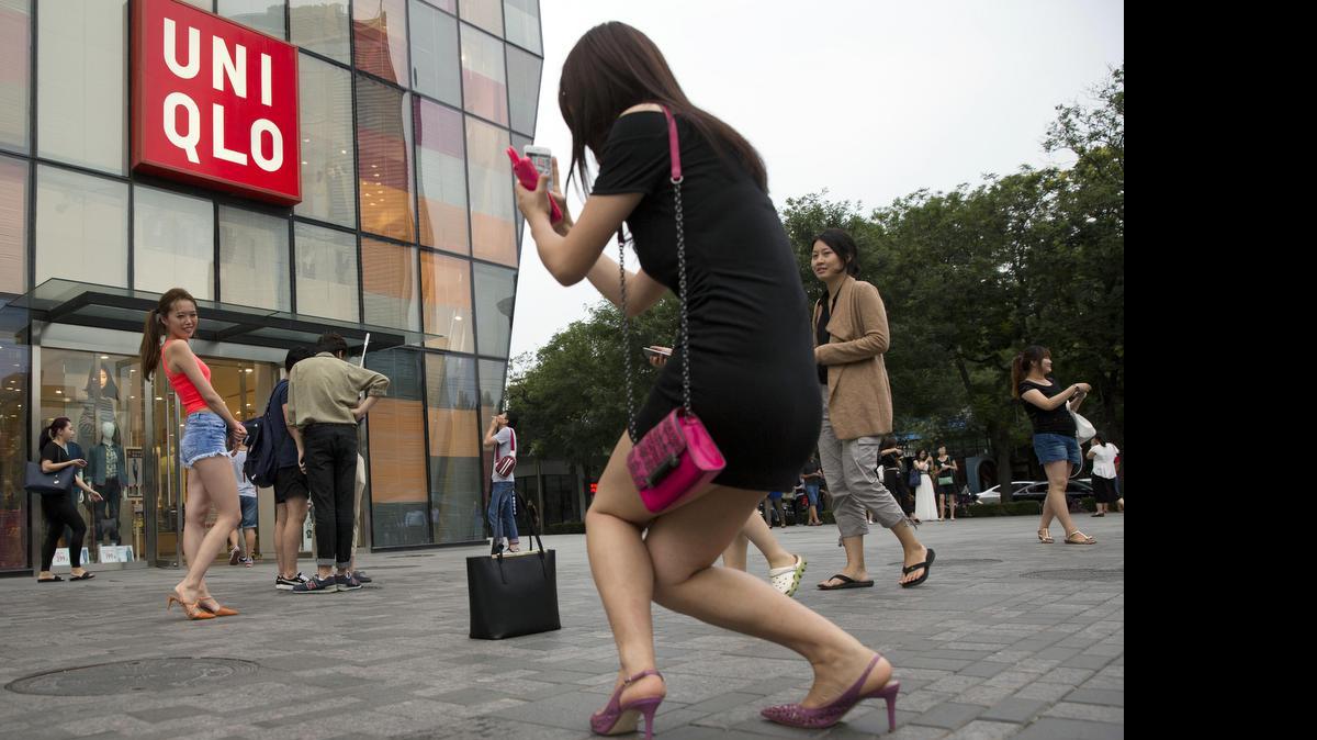 
Una joven china posa para otra que le toma una foto frente a la tienda japonesa Uni Qlo, en Pekín, en la cual se filmó ilegalmente un vido pornográfico, según dicen las autoridades chinas.
