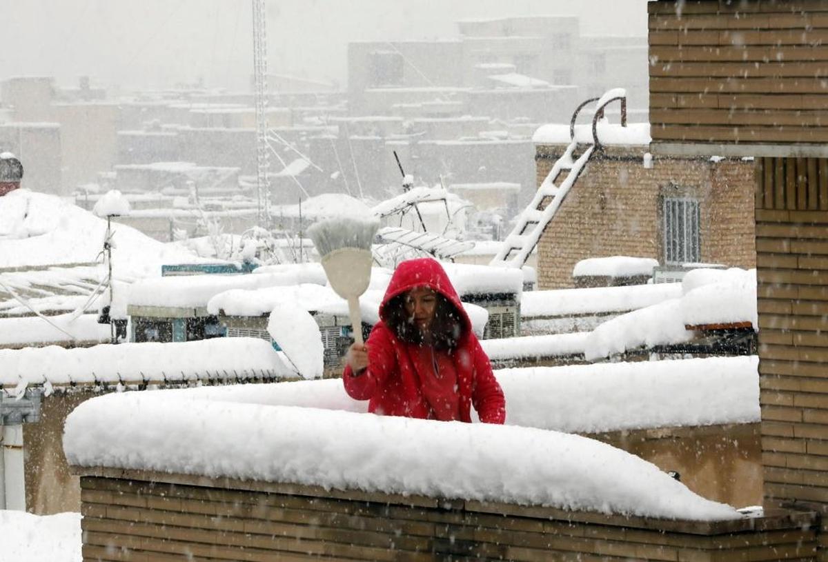 Una mujer limpia el techo de su casa en Teherán durante la nevada el 28 de enero del 2018.