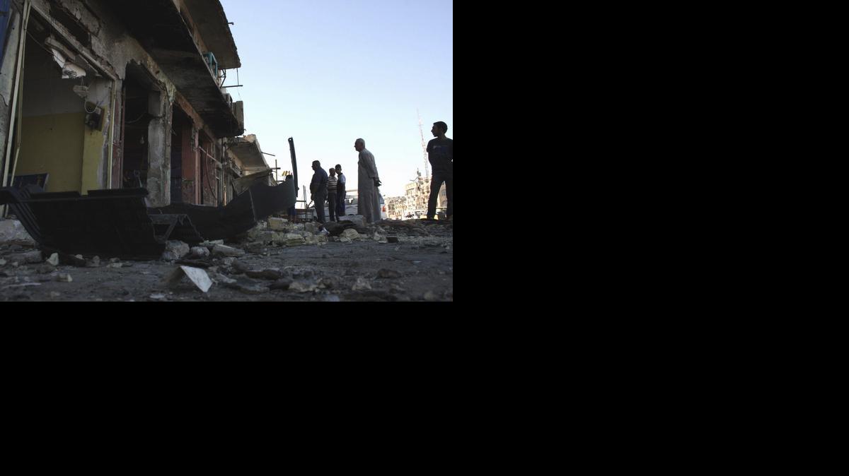 
Curiosos observan el lugar donde un carro-bomba explotó matando a una docena de personas, en Bagdad, Irak.
