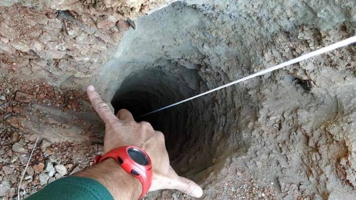 Un guardia civil señala el orificio, de apenas 30 centímetros de ancho, del pozo de más de 100 metros de profundidad por el que cayó un niño de dos años en una finca privada de la localidad malagueña de Totalán.