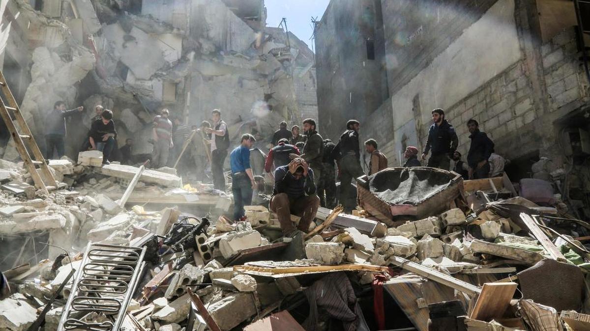 Un sirio lamenta la muerte de conocidos mientras miembros de los voluntarios de la defensa civil siria, también conocidos como Cascos Blancos, buscan a sobrevivientes entre los escombros después de ataques aéreos en la ciudad de Saqba, en Ghouta Oriental, el 4 de abril de 2017.