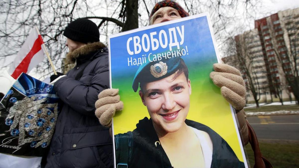 Varios bielorrusos muestran retratos de la ex piloto ucraniana Nadezhda Savchenko con el lema "Libertad para Savchenko" durante una concentración de apoyo ante la Embajada de Rusia en Minsk.