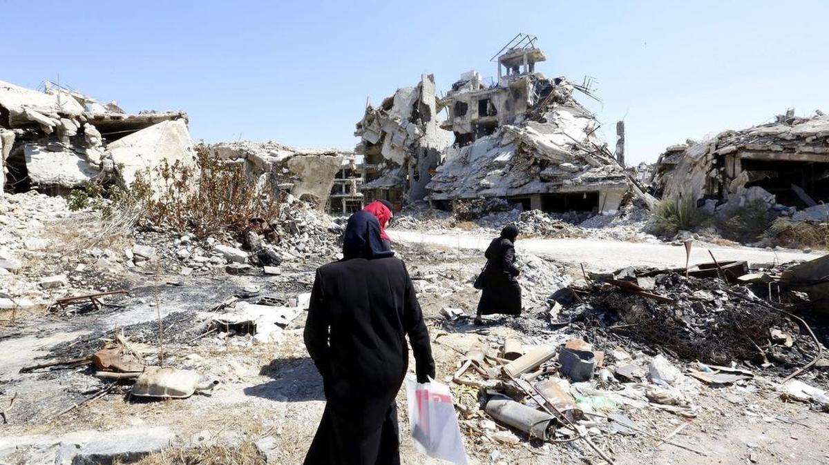 Mujeres sirias caminan entre las ruinas de la ciudad Homs. La comandancia suprema de las fuerzas armadas sirias declaró el fin de la tregua de una semana en el país árabe.