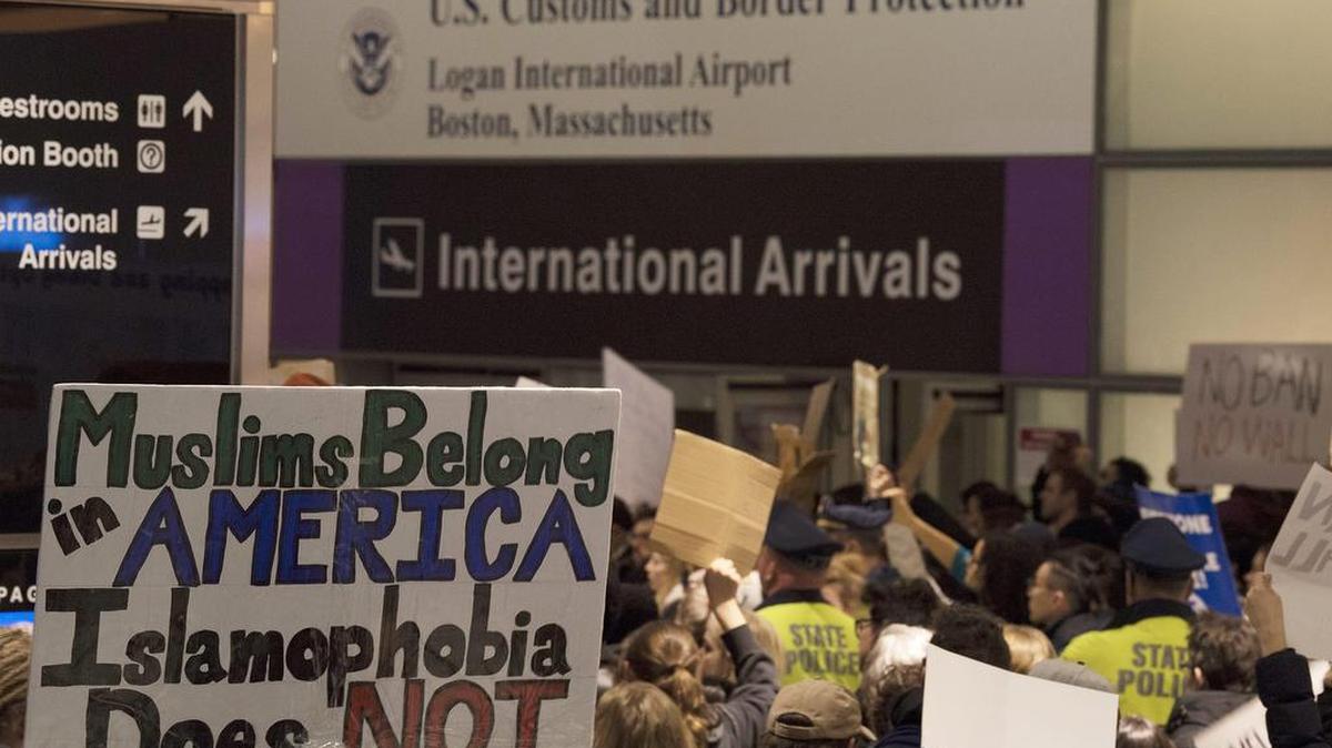 Cientos de personas protestan el domingo en la terminal de llegadas internacionales en el Aeropuerto Internacional Logan en Boston.