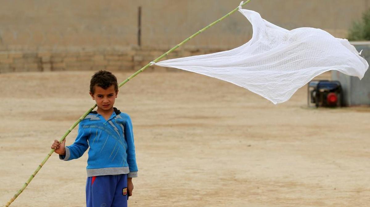 Un niño iraquí que fue desplazado de la aldea de Abu Shuwayhah, al sur de la mezquita yihadista de Mosul, camina con una bandera blanca mientras los lugareños regresan a su aldea después de la llegada de las fuerzas iraquíes el 1 de noviembre de 2016.