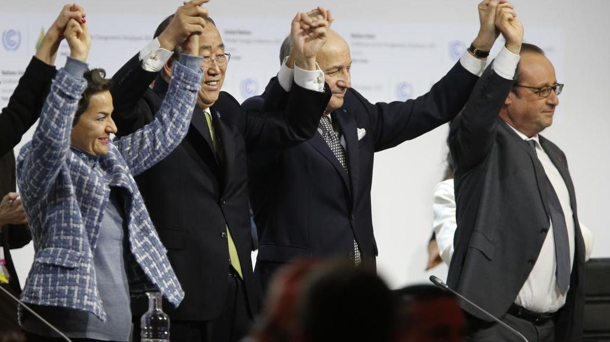 El canciller francés Laurent Fabius (centro) levanta los brazos junto con el secretario general de la ONU y el presidete galo Francois Hollande (derecha) tras concretarse el acuerdo en París este sábado.