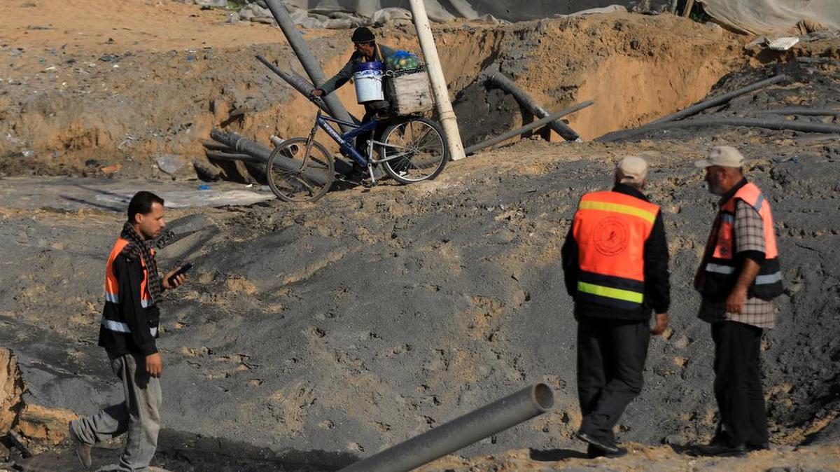 Se ve a personas alrededor de una carretera dañada después de los ataques aéreos israelíes en la ciudad de Khan Younis, en el sur de la Franja de Gaza, 2 de diciembre de 2023.