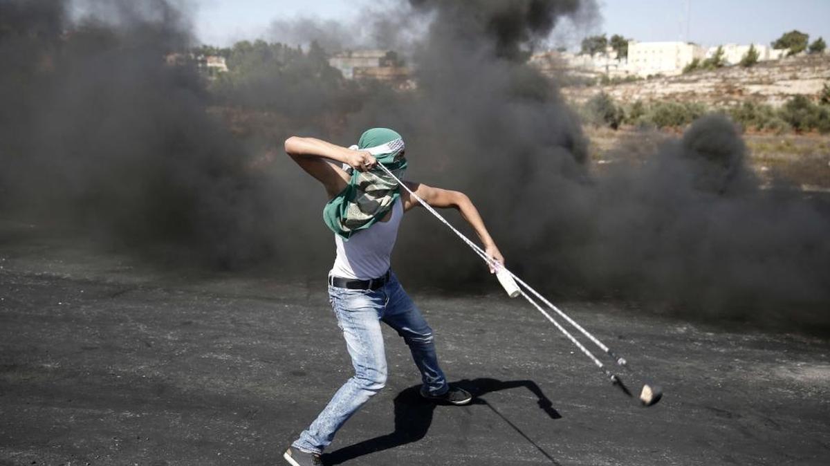 
Un manifestante palestino lanza piedras a las fuerzas de seguridad israelíes durante enfrentamientos en Beit El, cerca de Ramalá, el 11 de octubre.


