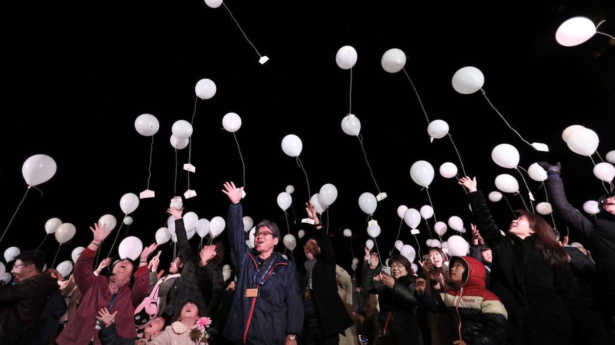 Personas liberan globos blancos, llevando sus deseos, para celebrar el Año Nuevo en la Torre Prince Park en Tokio el 1 de enero de 2017.