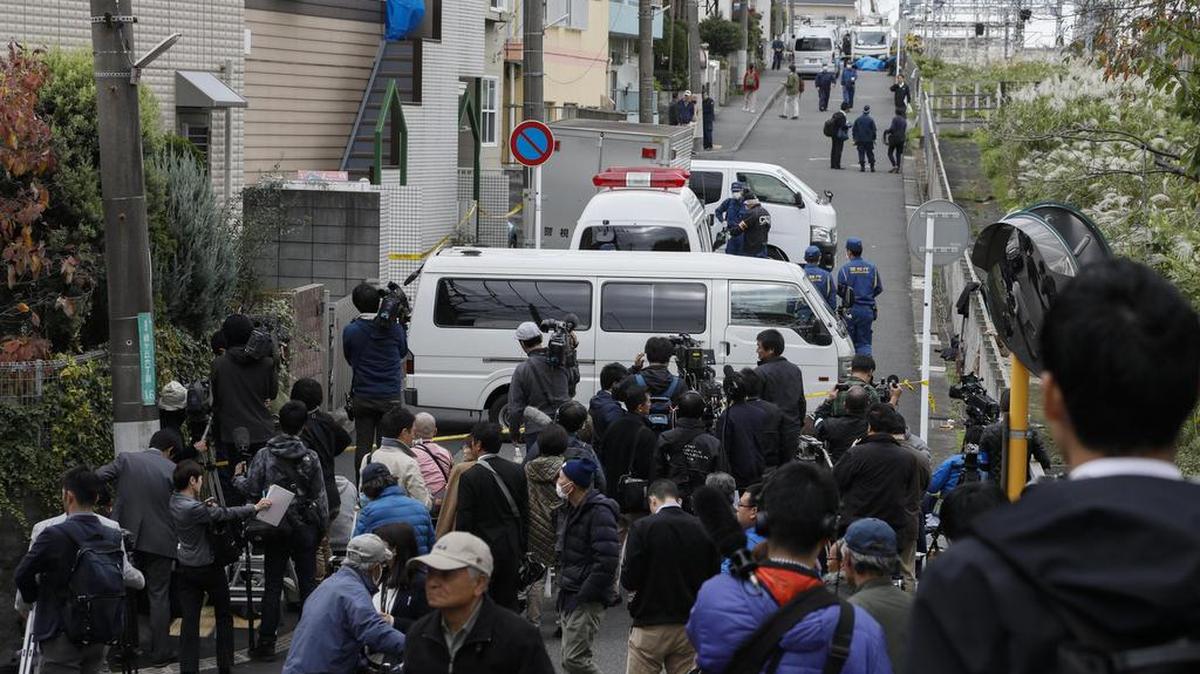 Investigadores policiales vigilan un edificio de departamentos, mientras los miembros de la prensa se aglomeran el martes 31 de octubre de 2017, en Zama (Japón).