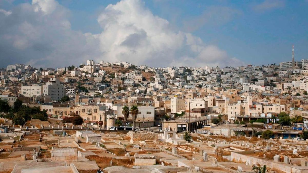Esta foto de archivo tomada el 09 de octubre de 2017 muestra el asentamiento israelí de Abraham Avino rodeado de casas palestinas (arriba) y un cementerio (abajo) en la ciudad dividida de Hebrón en el Banco de Wets ocupado por Israel. Las autoridades israelíes, el 16 de octubre de 2017, aprobaron los permisos para 31 hogares de colonos en Hebrón, en la Cisjordania ocupada, las primeras aprobaciones de la ciudad desde 2002, dijo la ONG Peace Now.