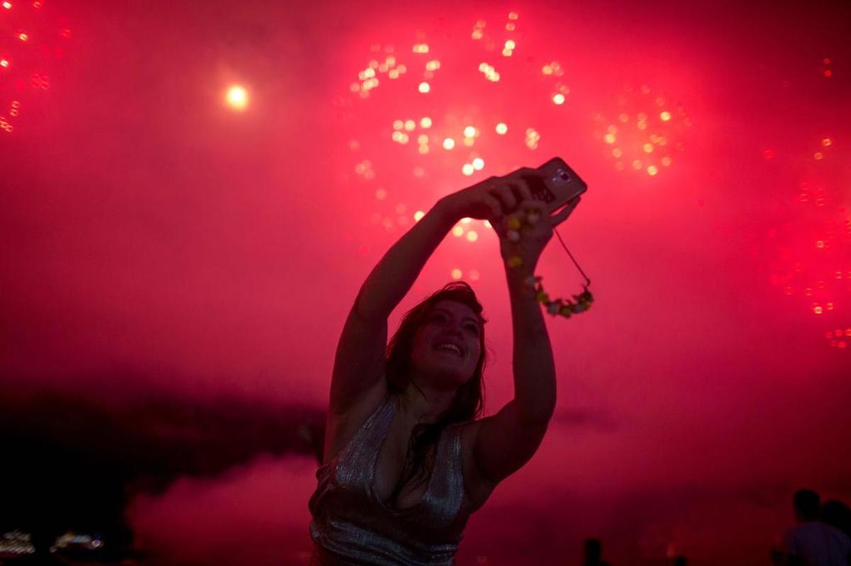 Una mujer toma fotos de los fuegos artificiales durante las celebraciones de Año Nuevo en la playa de Copacabana en Río de Janeiro el 1 de enero de 2018.