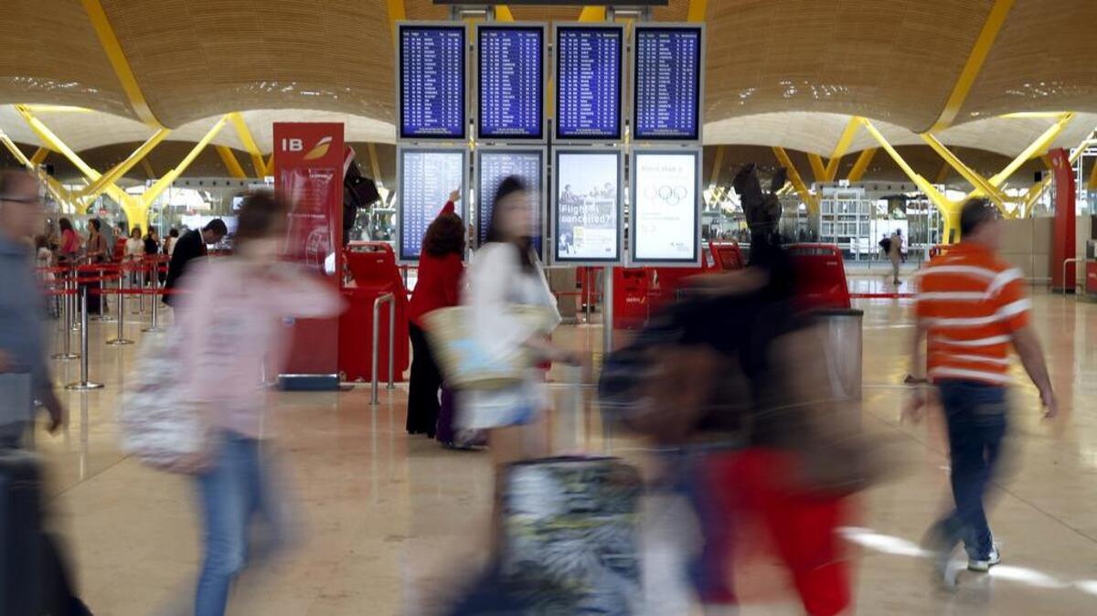 Viajeros esperan la salida de sus vuelos en la T4 del aeropuerto de Madrid Barajas en julio.