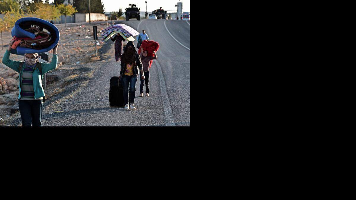 
Residentes de áreas cercanas a Kobane huyen el domingo ante la inminente llegada de las fuerzas del Estado Islámico a esa zona.


