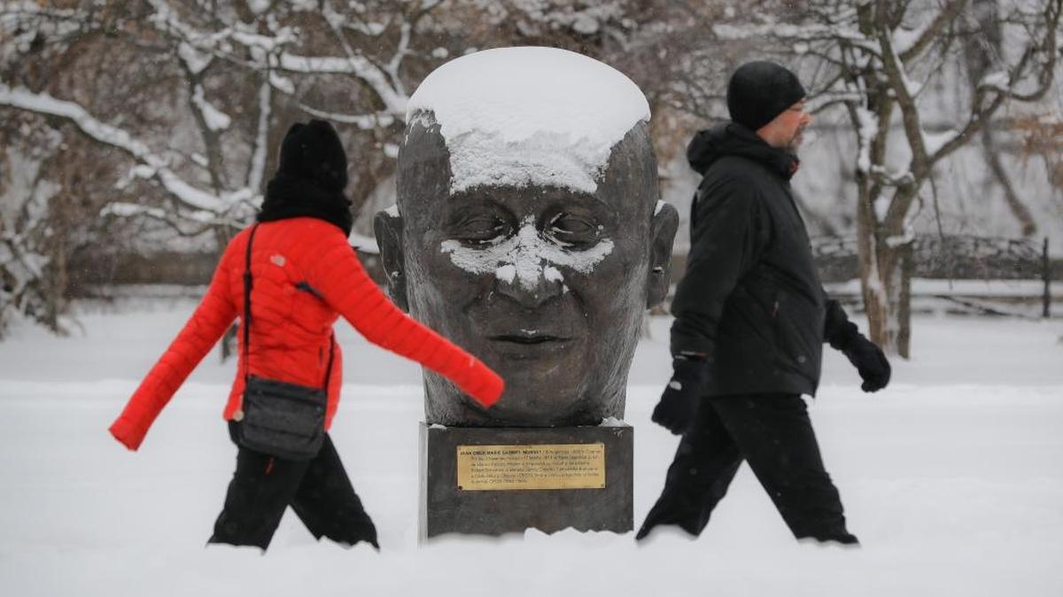 Dos personas pasan ante una estatua del diplomático francés Jean Monnet, en un parque de Bucharest, Rumania. El país se prepara para una intensa ola de frío.