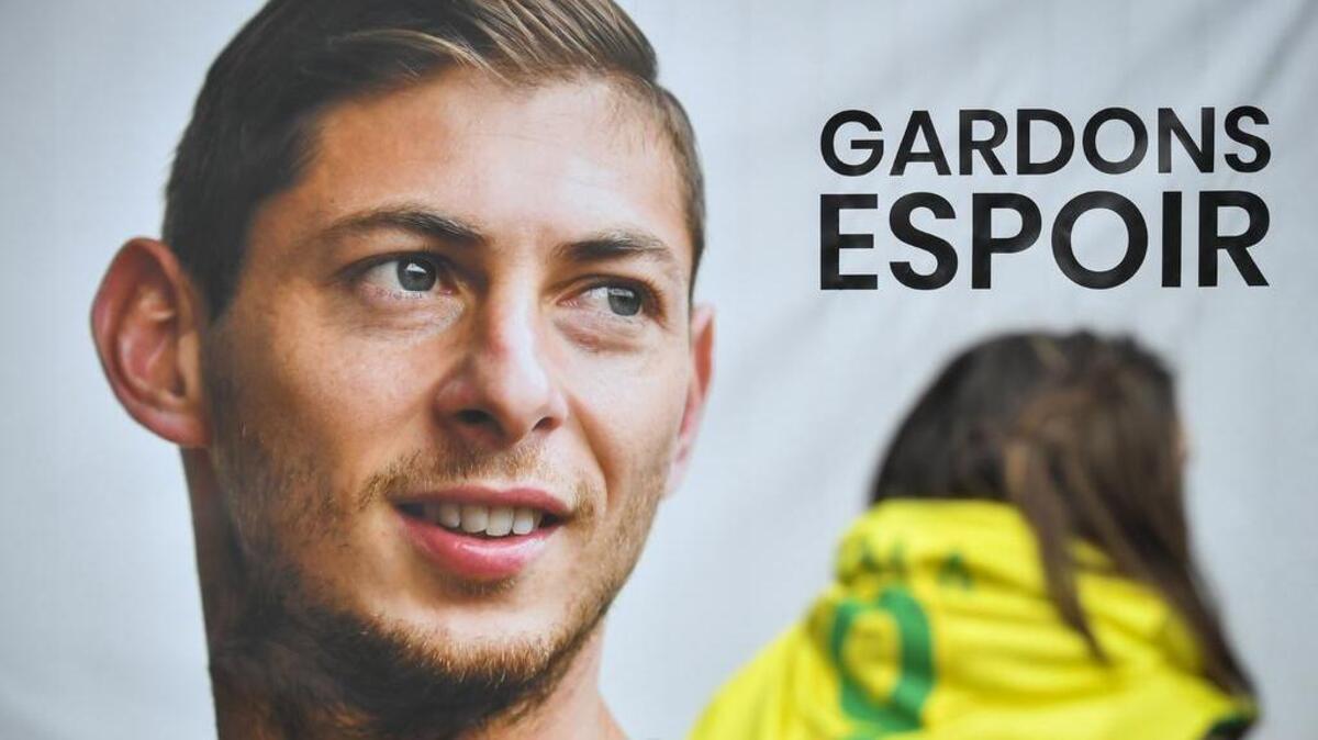 Un partidario del FC Nantes pasa frente a un cartel del delantero argentino Emiliano Sala antes de una sesión de entrenamiento del equipo en el centro de entrenamiento La Joneliere en La Chapelle-sur-Erdre, el oeste de Francia, el 24 de enero de 2019, tres días después de que el avión que llevaba a Sala desapareciera. sobre el canal de ingles.