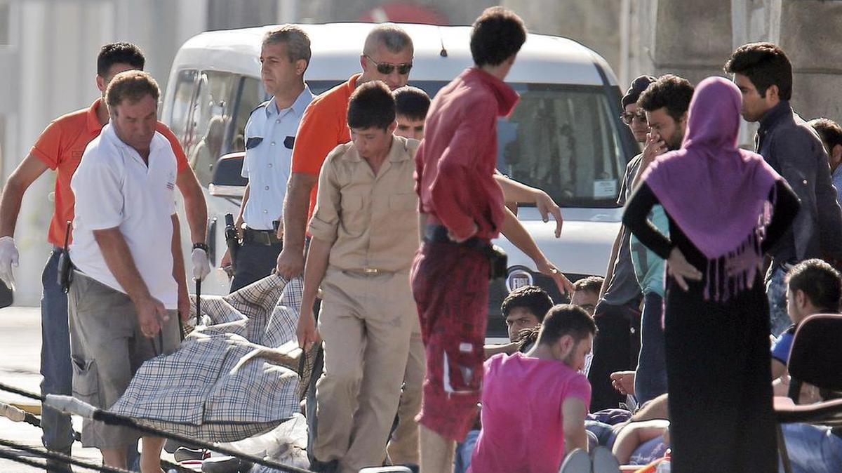 
Migrantes que fueron rescatados a bordo de un guardacosta turco cargan el cadáver en el puerto de Bodrum.
