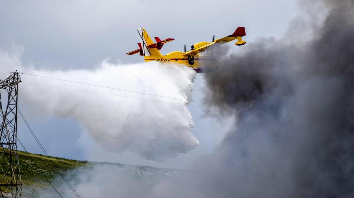 Un avión de la nUnidad Militar de Emergencias trabaja en labores de extinción del incendio producido hoy en el cementerio de neumáticos de Seseña (Toledo), un tercio del cual se encuentra en el término municipal de Valdemoro (Madrid) y que acumula miles de toneladas de ruedas, lo que ha provocado que Castilla-La Mancha haya activado el nivel 1 del plan de emergencia por el humo.