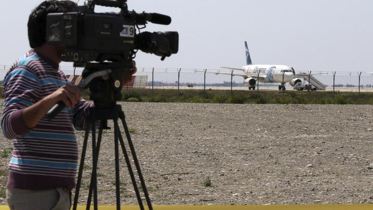 Un operador de cámara toma imágenes del avión de Egiptair secuestrado por un pasajero con un cinturón explosico en el aeropuerto de Larnaca (Chipre).