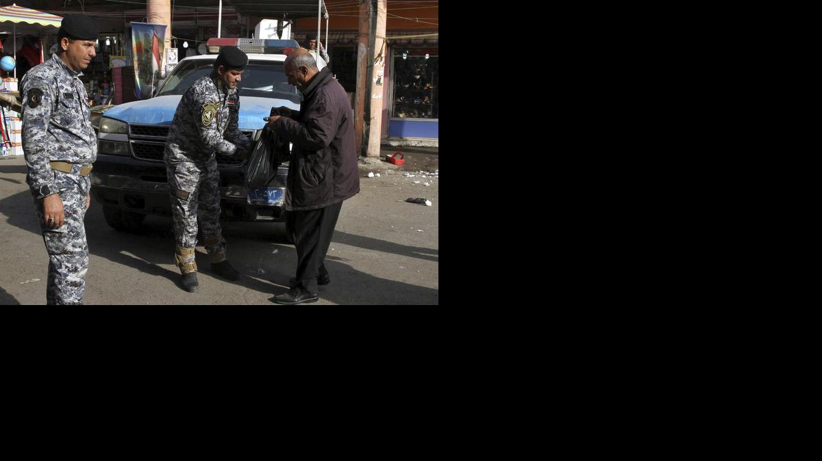 
Policias iraquies registran la bolsa de un civil en un mercado callejero tras la explosión de una casa en la aldea de Al Suyairi, en Bagdad, Irak, el viernes. 



