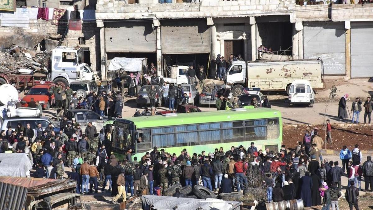 Civiles, rebeldes y sus familiares se aprestan a subir a los autobuses para salir de Alepo este jueves.