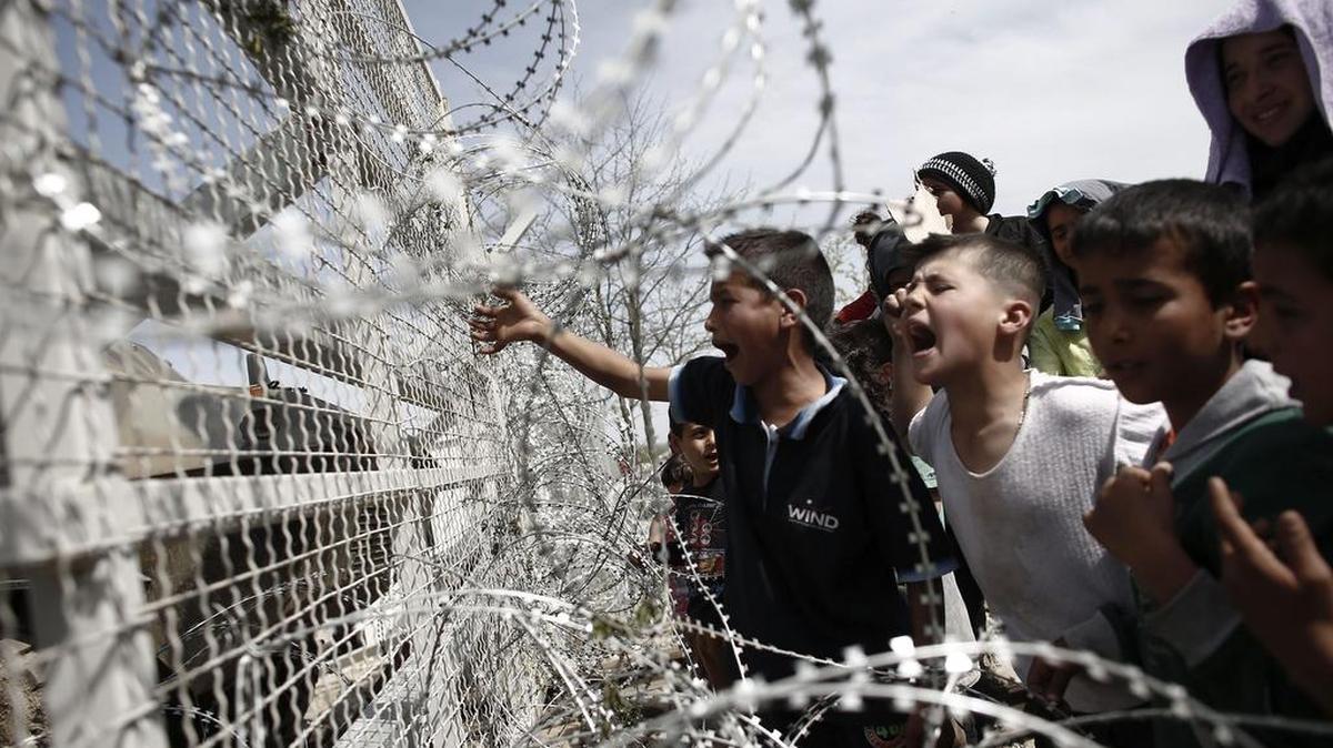 Varios niños se manifiestan en frente de una alambrada por la apertura de las fronteras a Macedonia en el campo improvisado de refugiados de Idomeni, Grecia.