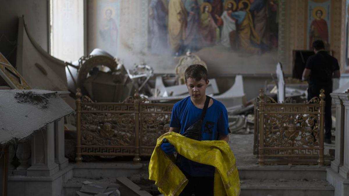 Un niño ayuda a rescatar artículos en la Catedral de la Transfiguración de Odesa, después de que sufriera graves daños por los ataques con misiles rusos este domingo.