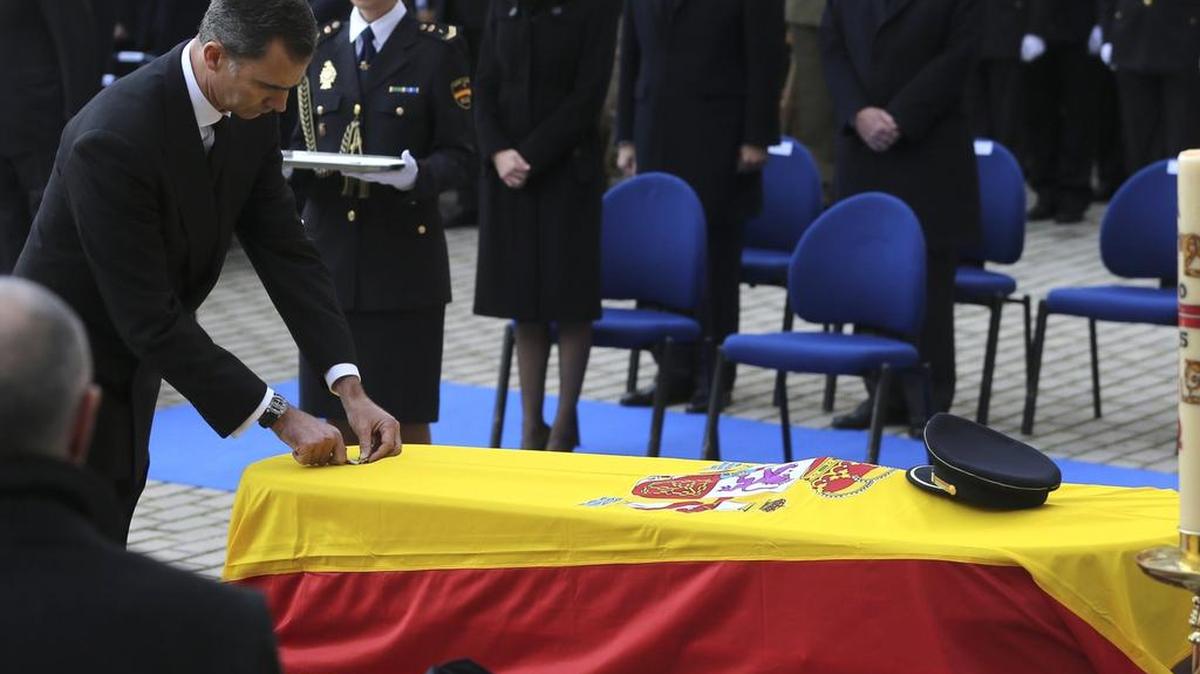 El rey Felipe VI impuso la Cruz de Oro al Mérito Policial a los féretros de los policías, que estuvieron cubiertos por banderas de España y sus gorras policiales.