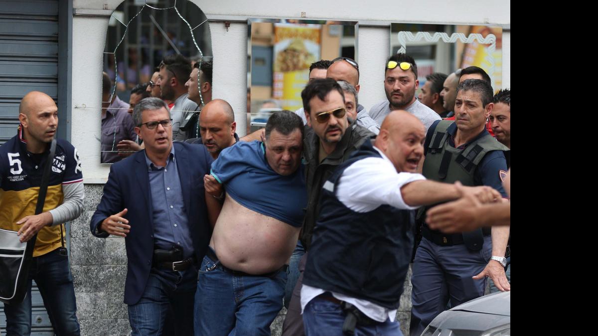 
 Un hombre con camiseta azul (c) es detenido por ser sospechoso de protagonizar el tiroteo desde su terraza en la que ha matado a cuatro personas y ha herido a otros cinco en el barrio de Secondigliano, Nápoles, Italia hoy 15 de mayo de 2015. 
