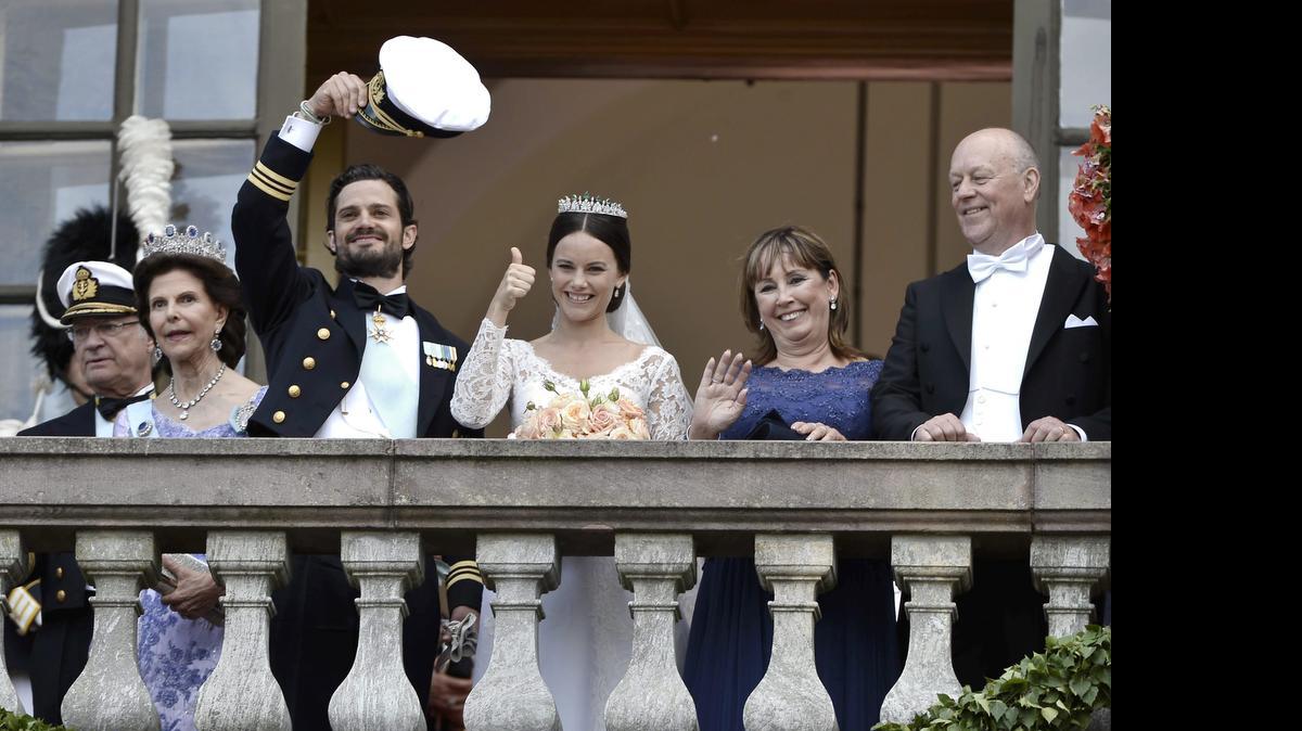 
La ex modelo y ex estrella de televisión Sofía Hellqvist (cent.), hace una señal de victoria junto a su esposo el príncipe Carlos Felipe de Suecia que saludo con su gorra de capitán naval. 
